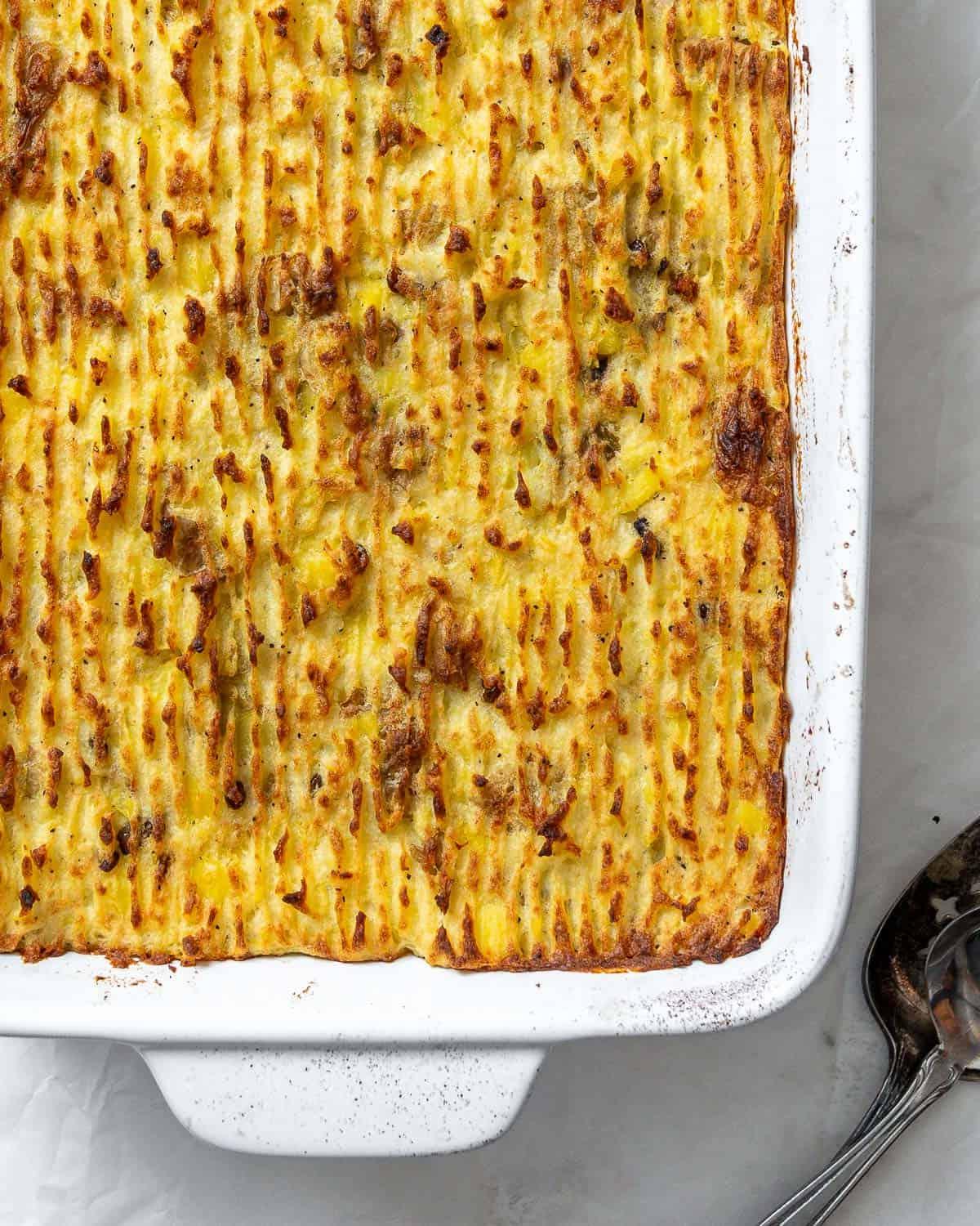 Veganer Linsen-Hirtenkuchen 22 Eine angeschnittene Portion veganen Linsen-Hirtenkuchens, die Textur der Füllung und des Pürees ist sichtbar