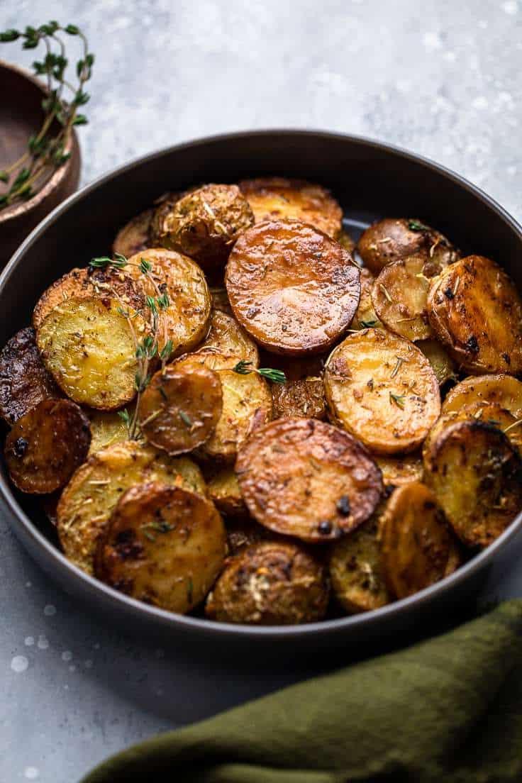 30 einfache vegane Kartoffelrezepte 24 Fertige Zitronen-Rosmarin-Schmelzkartoffeln auf einem schwarzen Teller