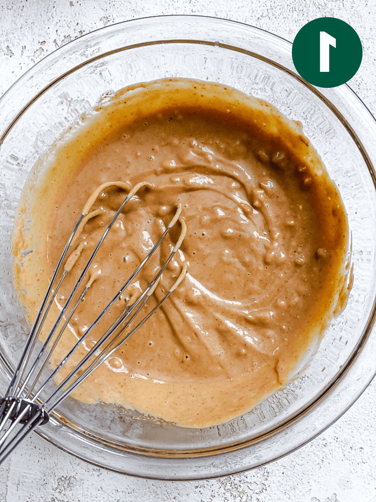 whisking peanut sauce in a glass bowl.