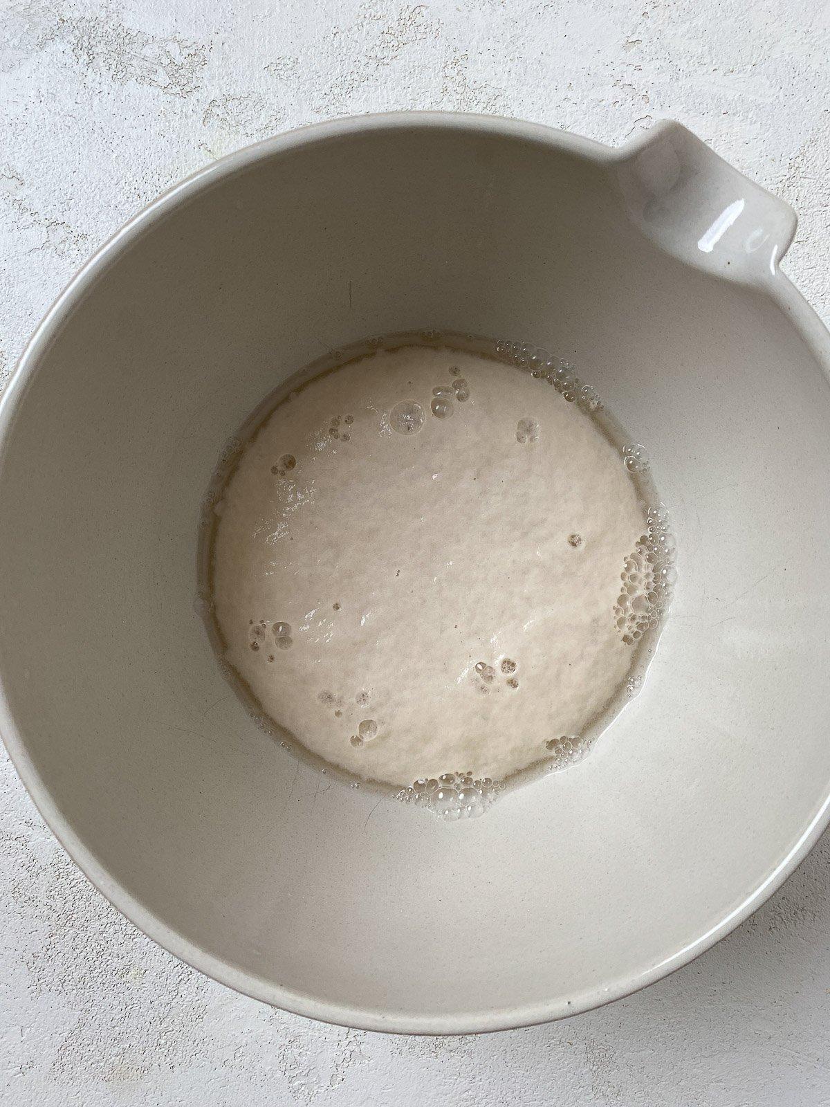 Vegane Pizzaröllchen 3 yeast and sugar with water in a white bowl