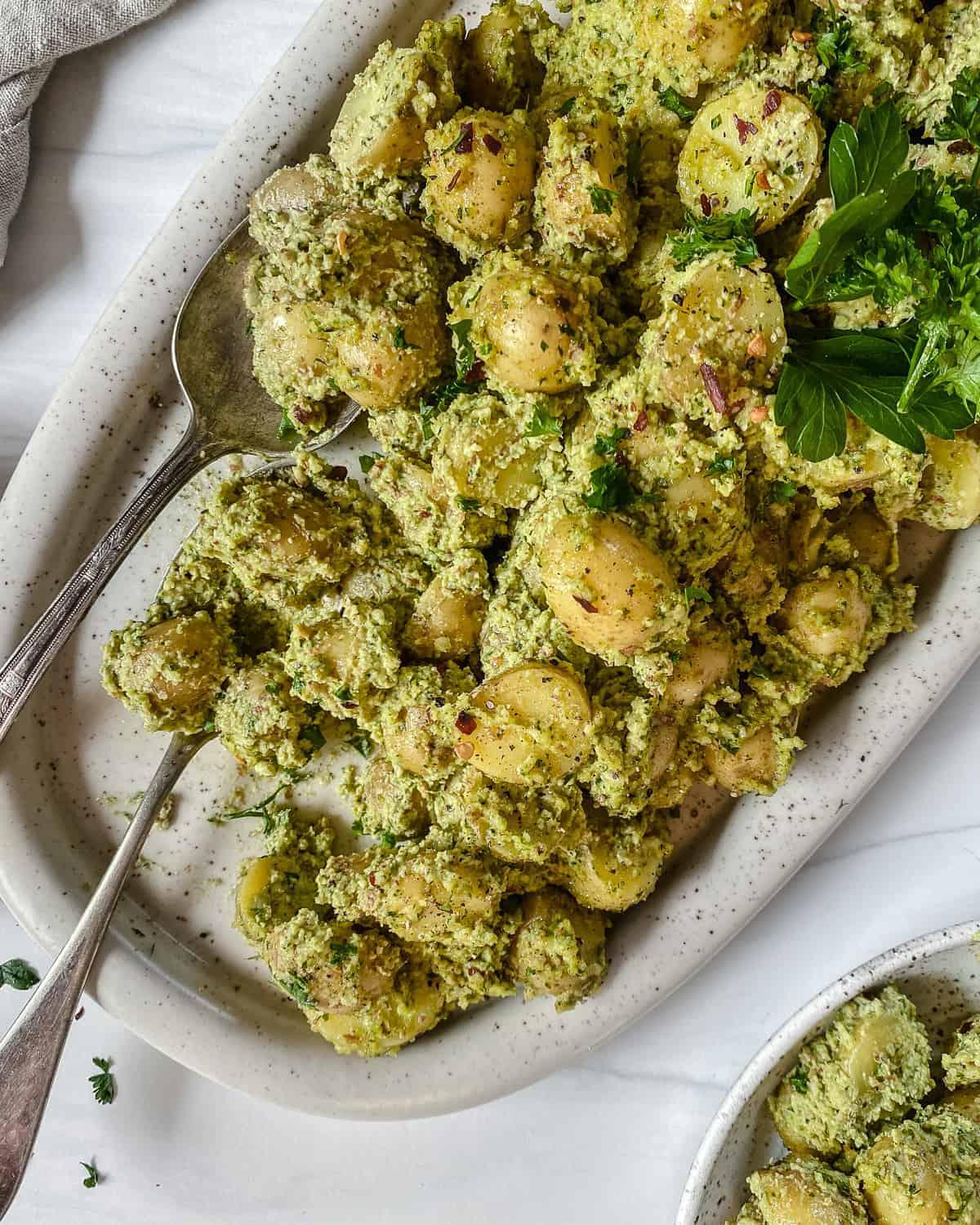 30 einfache vegane Kartoffelrezepte 4 Fertige Mandel-Petersilienkartoffeln in einer weißen Auflaufform auf weißem Hintergrund