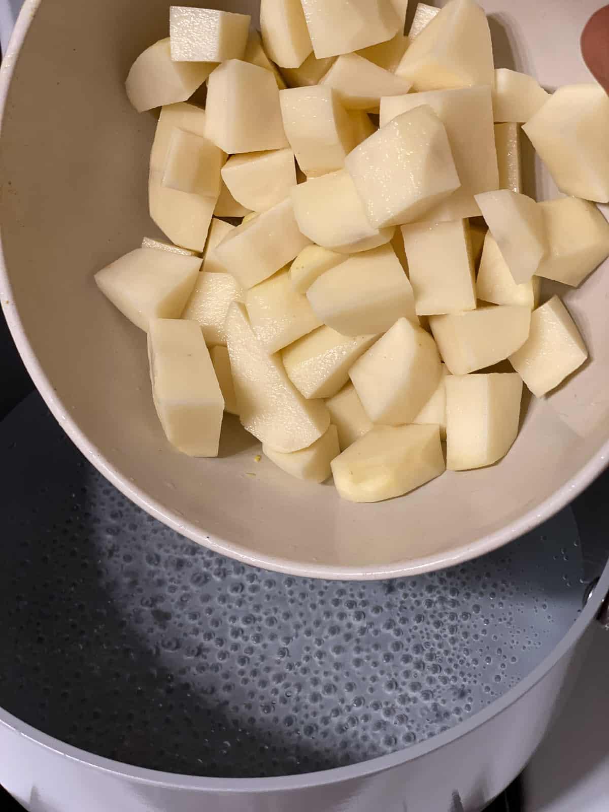 Cremige geröstete rote Paprikasuppe 4 Gewürfelte Kartoffeln in einer Schüssel über einer Pfanne