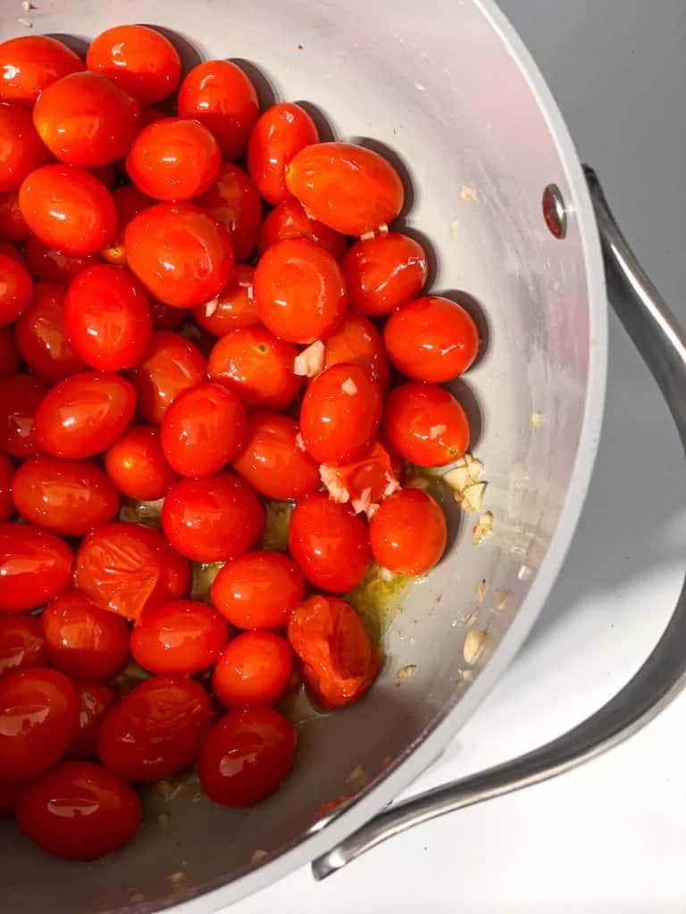 15-Minuten-Kirschtomaten-Basilikum-Pasta 4 Zubereitungsschritt: Frische Kirschtomaten und Knoblauch kochen in einer Pfanne mit Olivenöl und beginnen weich zu werden