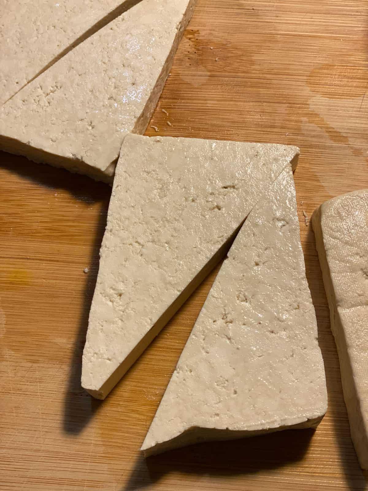 Einfacher Zitronen-Basilikum-Tofu 4 Prozess des Schneidens von Tofu in Dreiecke auf einem Schneidebrett