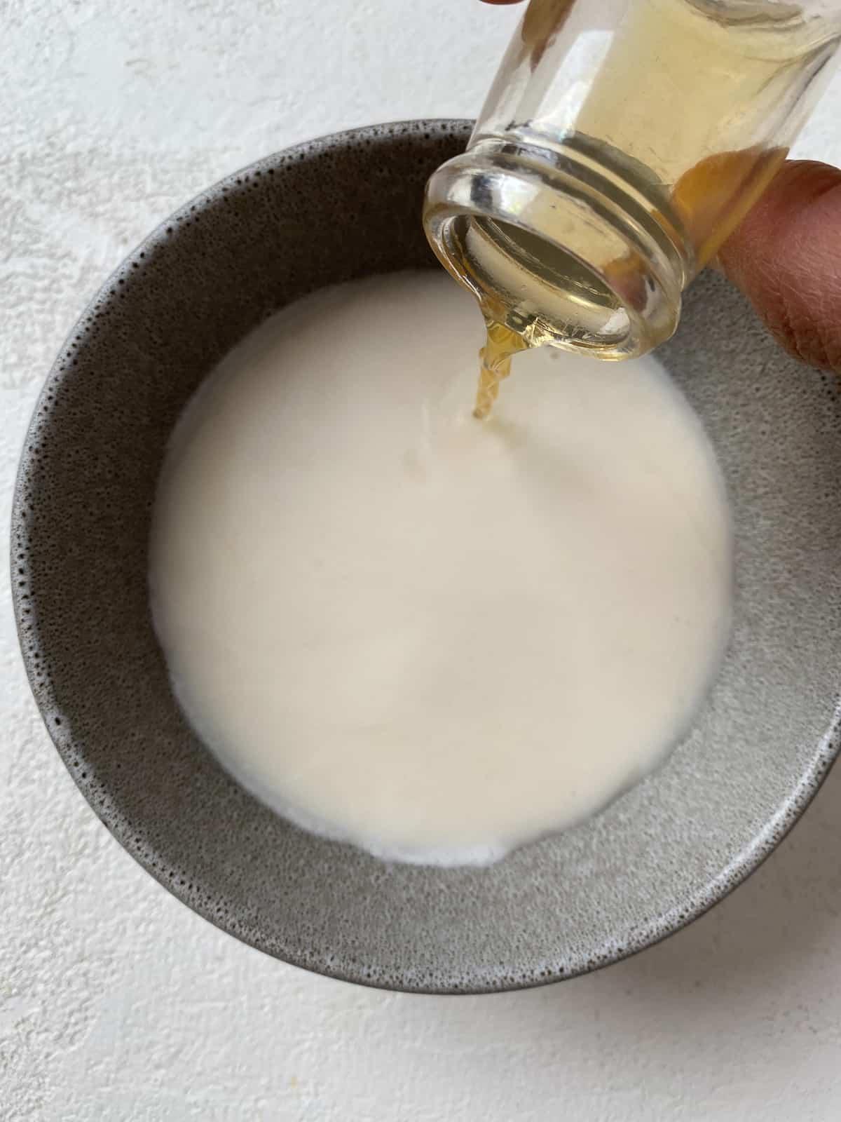 Butternusskürbis-Salbei-Gebäck 4 Apfelessig wird in eine Schüssel mit pflanzlichem Drink gegossen.