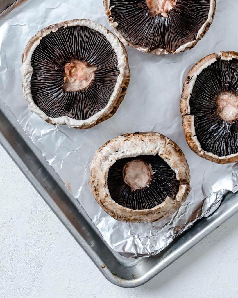 Portobello-Pilz-Pizzen 4 Portobello-Pilze auf einem mit Backpapier ausgelegten Backblech