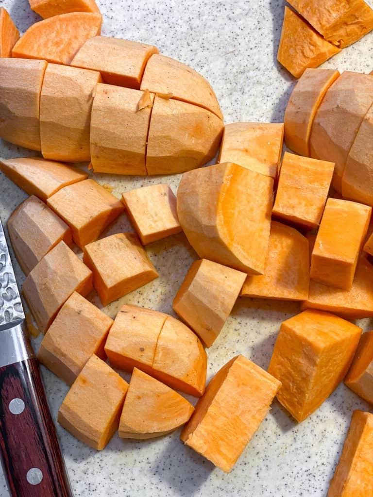 Veganer Süßkartoffelkuchen 4 Gewürfelte Süßkartoffeln auf einer weißen Oberfläche