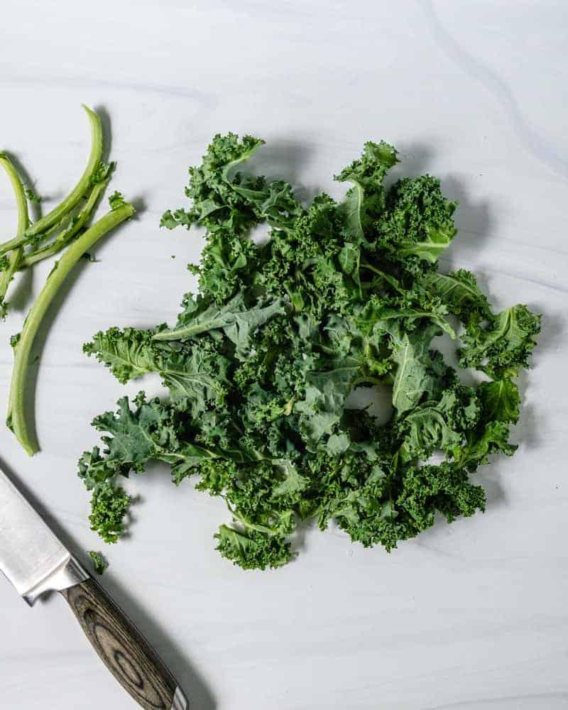 Curly Kale Removing Stem on a Marble Surface 