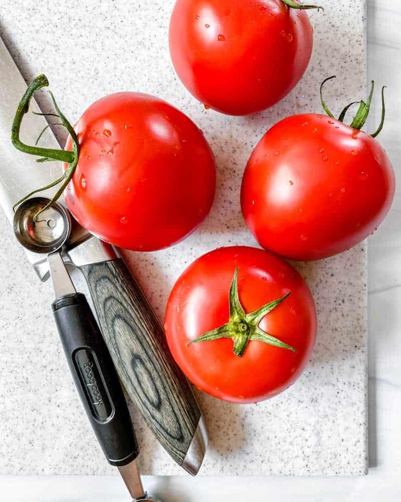 Gefüllte Tomaten 5 Vier rohe Tomaten auf einem Schneidebrett