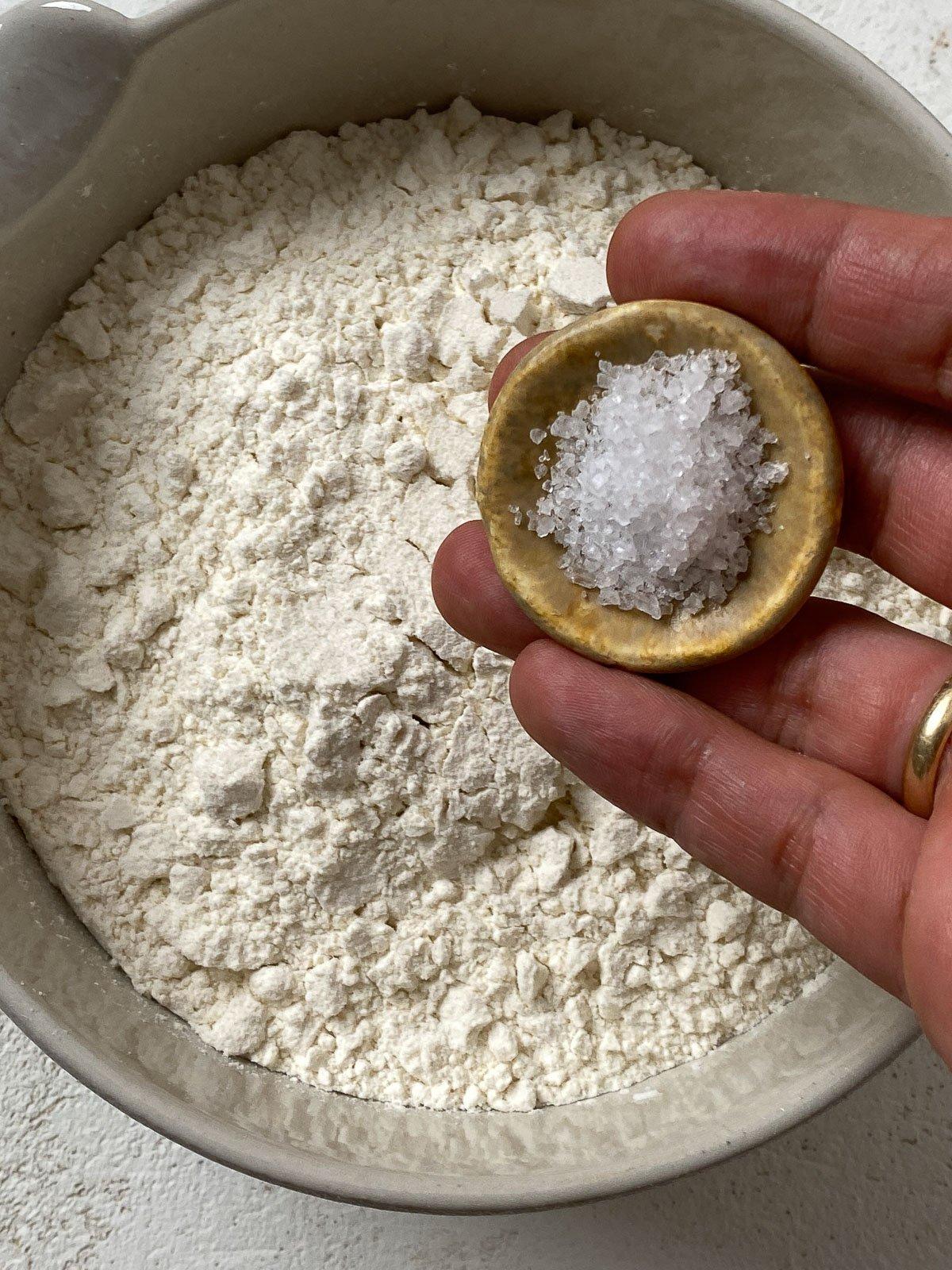 Vegane Pizzaröllchen 4 adding salt to bowl of flour in a bowl