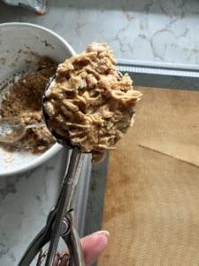 Vegane Schoko-Erdnussbutter-Kugeln ohne Backen mit Reis-Crispies 5 Schaufel mit Erdnussbutter-Bonbon-Zutaten vor einer Silikonmatte im Hintergrund