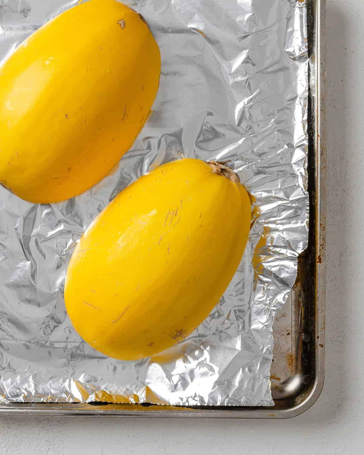 Chili-Käse-gefüllter Spaghettikürbis 5 halved squash on top of foil in baking tray