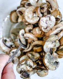 process of mixing mushrooms and ingredients in a white bowl