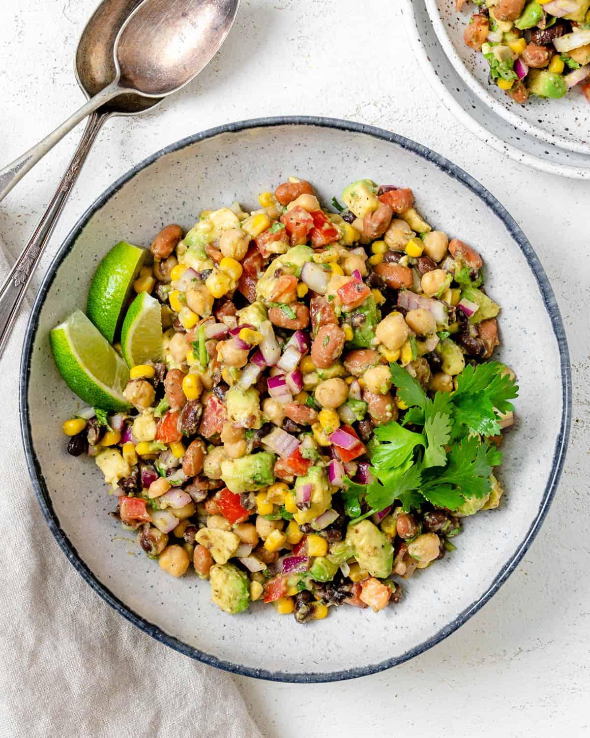 Fertiges Texas Caviar [Avocado-Mais-Bohnen-Salat] auf einem weißen Teller vor hellem Hintergrund