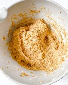 Veganes Kürbisbrot 5 Prozess des Mischens feuchter Zutaten für Kürbisbrot in weißer Schüssel vor weißem Hintergrund
