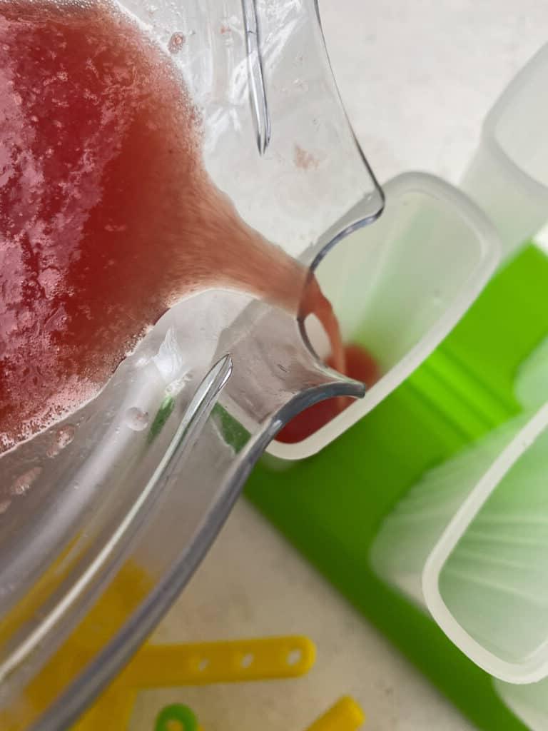 Gesundes Wassermelonen-Stieleis 5 Wassermelonenmischung wird in Eisförmchen gegossen