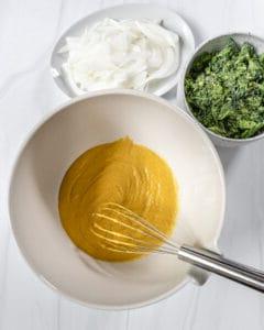 Zubereitungsprozess von Brokkoli- und Zwiebel-Pakora: feuchte Zutaten werden in einer Schüssel mit Zutaten daneben vermischt
