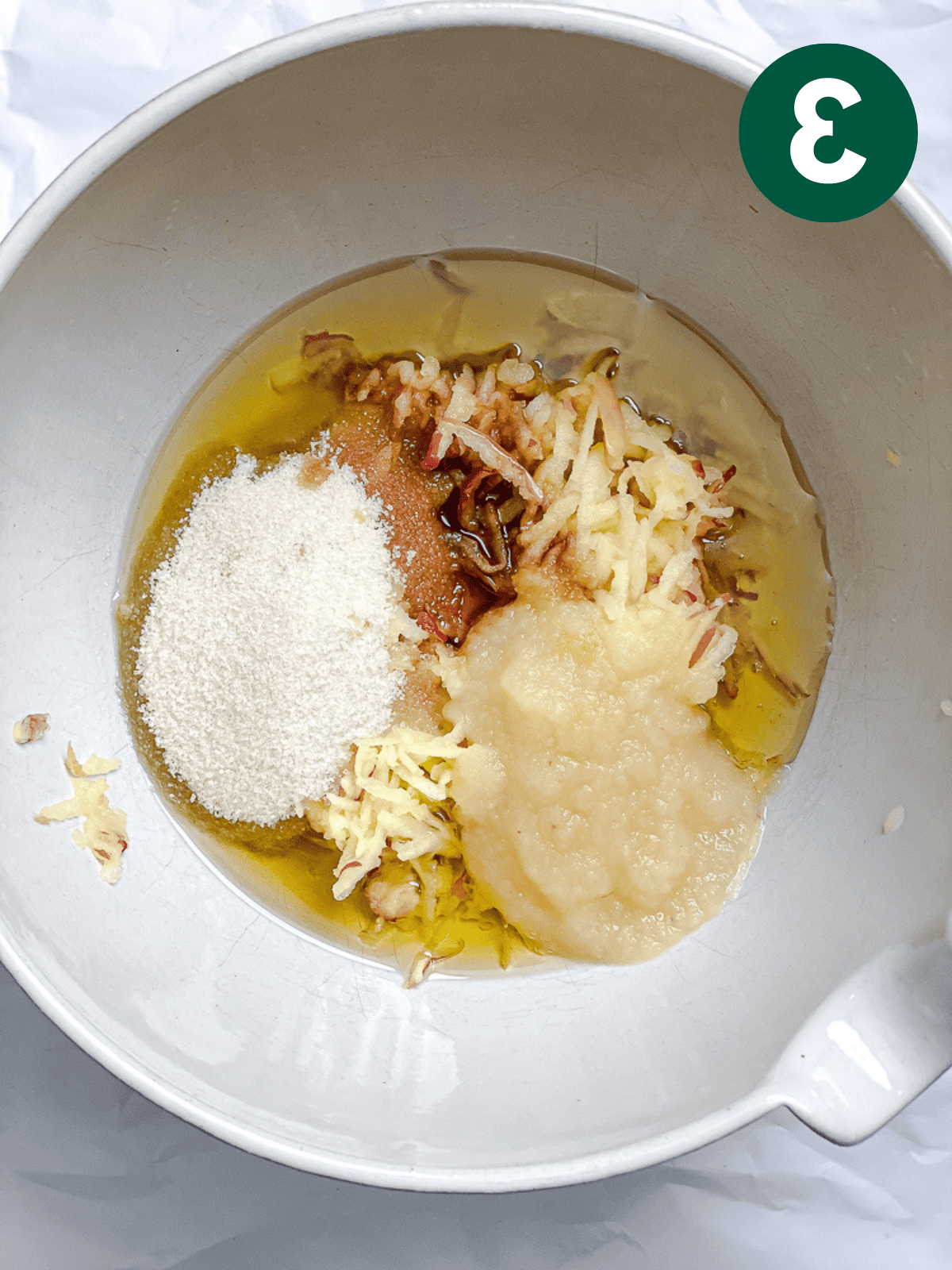 Apfel-Zimt-Brot 6 Die feuchten Zutaten für Apfel-Zimt-Brot mit einem weißen Spatel in einer großen weißen Schüssel verrühren.