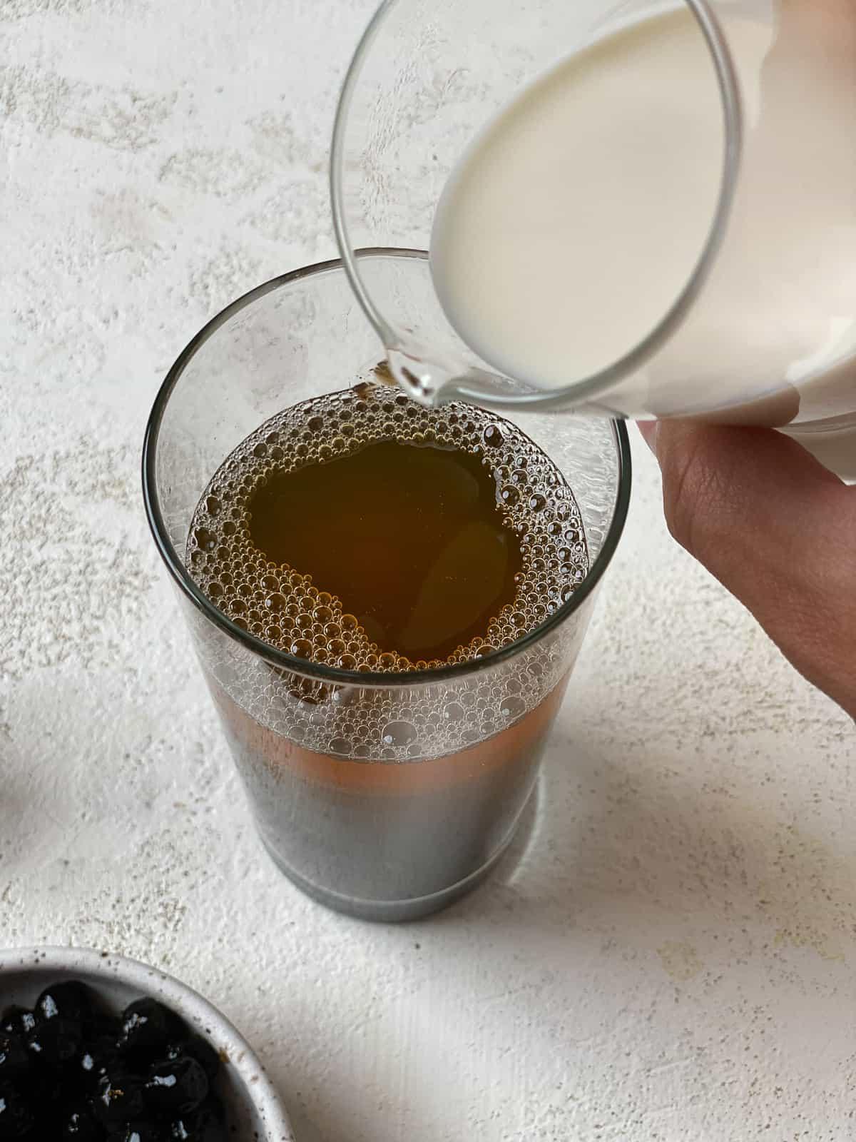 Einfacher Veganer Bubble Tea 6 process shot of pouring creamer into glass against a light background