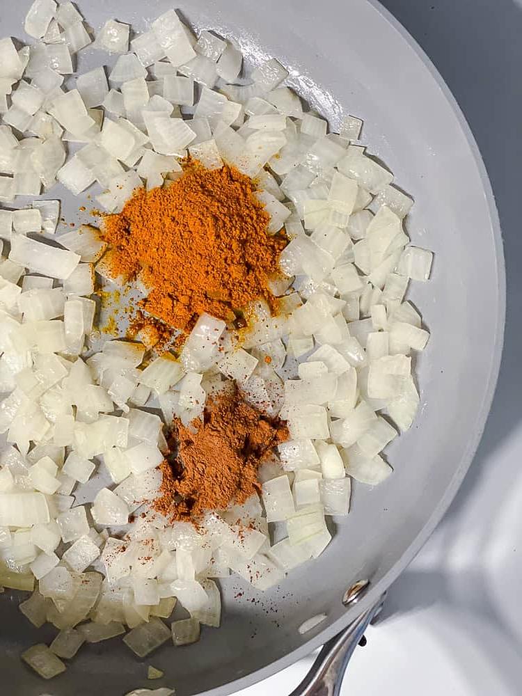 Curry-Kichererbsen 6 Prozessaufnahme: Zwiebeln werden in einer großen Pfanne mit Gewürzen angebraten.