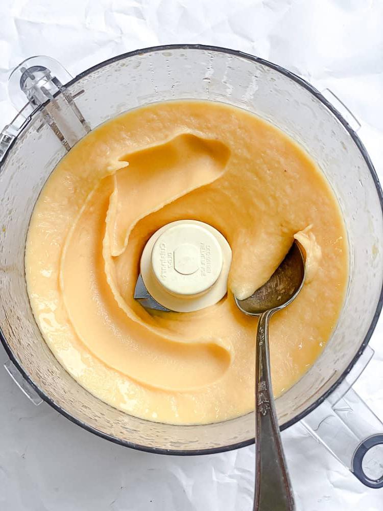 **Pfirsich Sorbet** 6 Mit einem Löffel gemischtes Pfirsich Sorbet in einer Küchenmaschine.
