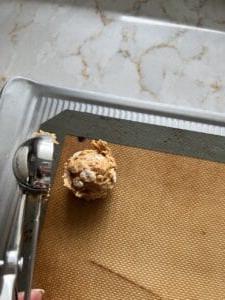 Vegane Schoko-Erdnussbutter-Kugeln ohne Backen mit Reis-Crispies 6 Prozess des Legens einer Kugel Erdnussbutter-Bonbons auf eine Silikonmatte