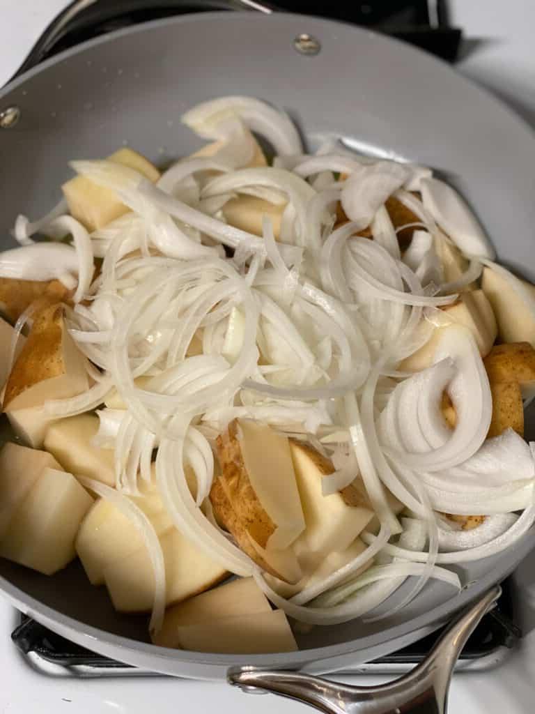 Knusprige Bratkartoffeln Rezept 6 Arbeitsschritt: Zwiebeln und Kartoffeln in der Pfanne vermischen