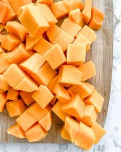 Gewürfelte Butternut-Kürbis mit Messer auf weißem Marmorhintergrund