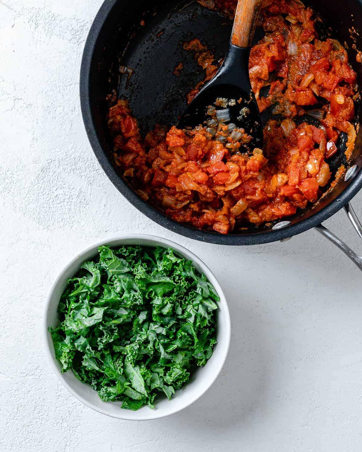 Portobello-Pilz-Pizzen 6 Zubereitungsschritt von Tomaten und Marinara in der Pfanne, daneben eine weiße Schale mit Grünkohl