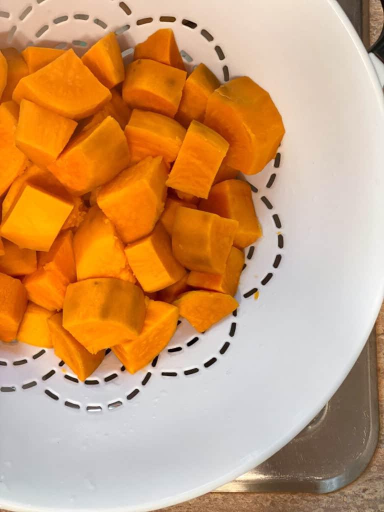 Veganer Süßkartoffelkuchen 6 Gewürfelte Süßkartoffeln in einem Sieb