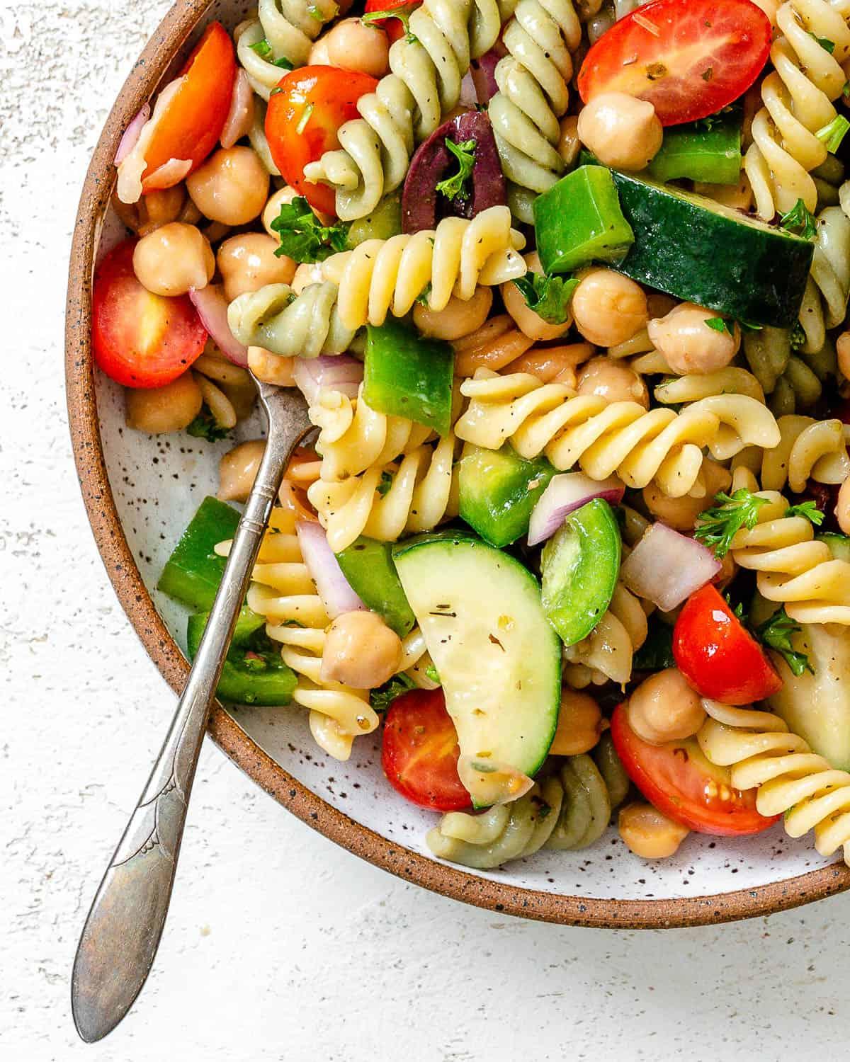 **Mediterraner veganer Nudelsalat** 6 Fertig angerichteter mediterraner veganer Nudelsalat auf weißem Untergrund