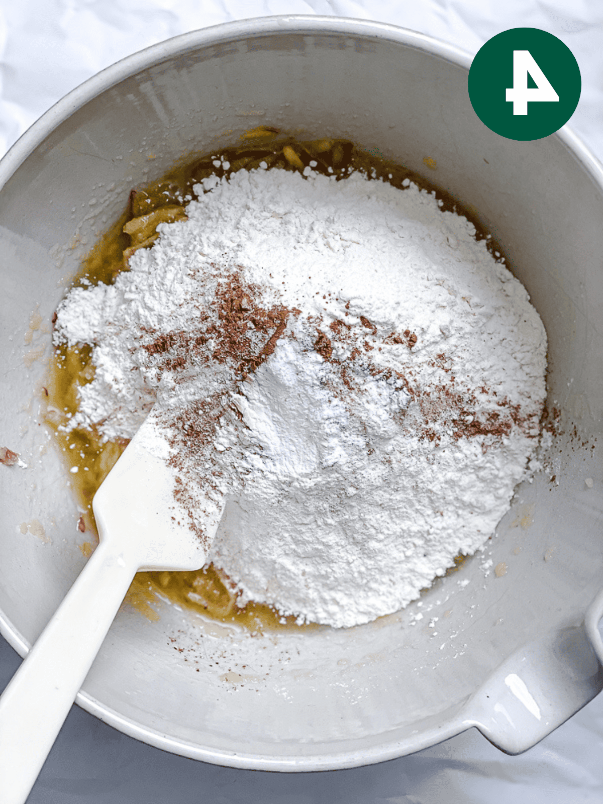 Apfel-Zimt-Brot 7 Die trockenen Zutaten für Apfel-Zimt-Brot mit einem weißen Spatel in einer großen weißen Schüssel verrühren.