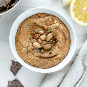 Gewürzter Bohnen-Dip 7 completed Spiced Refried Bean Dip in a bowl against a white background with ingredients spread in the back