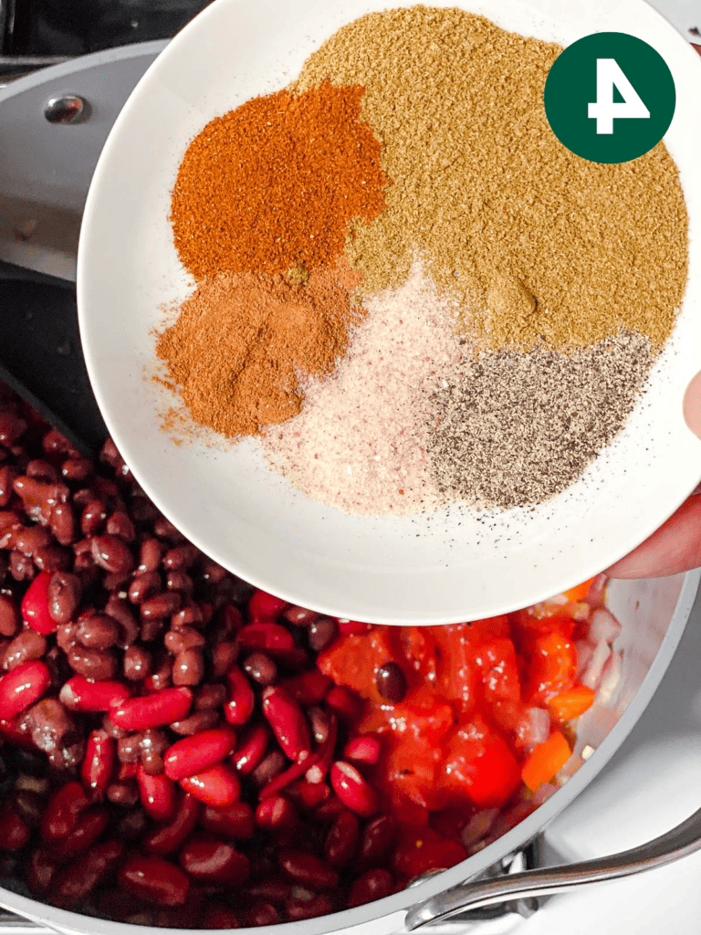 Veganes Kürbis-Chili für Schongarer und Herd 7 Prozessaufnahme des Hinzufügens von Gewürzen zur Pfanne