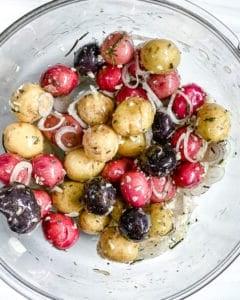 process of mixing Roasted Rosemary Potatoes ingredients in a bowl