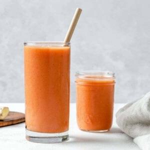 Ingwer-Frucht-Smoothie 7 Fertiger Ingwer-Frucht-Smoothie in einem hohen Glasbecher mit einem Papierstrohhalm im Vordergrund und einem kleinen Glas Smoothie im Hintergrund