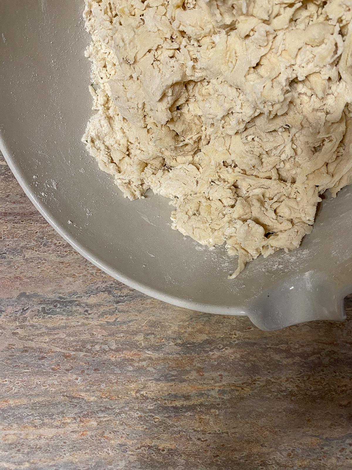 Vegane Pizzaröllchen 6 process of forming flour in a white bowl against a light brown surface