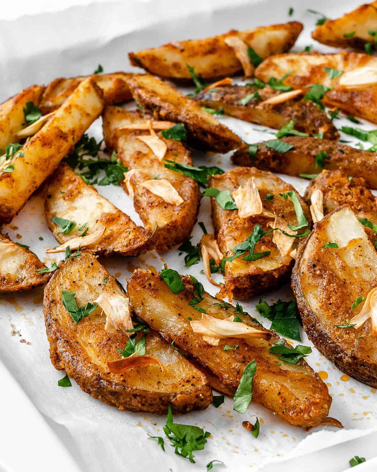 30 einfache vegane Kartoffelrezepte 7 Fertige Ofen-Knoblauch-Petersilien-Pommes auf einem Backblech verteilt