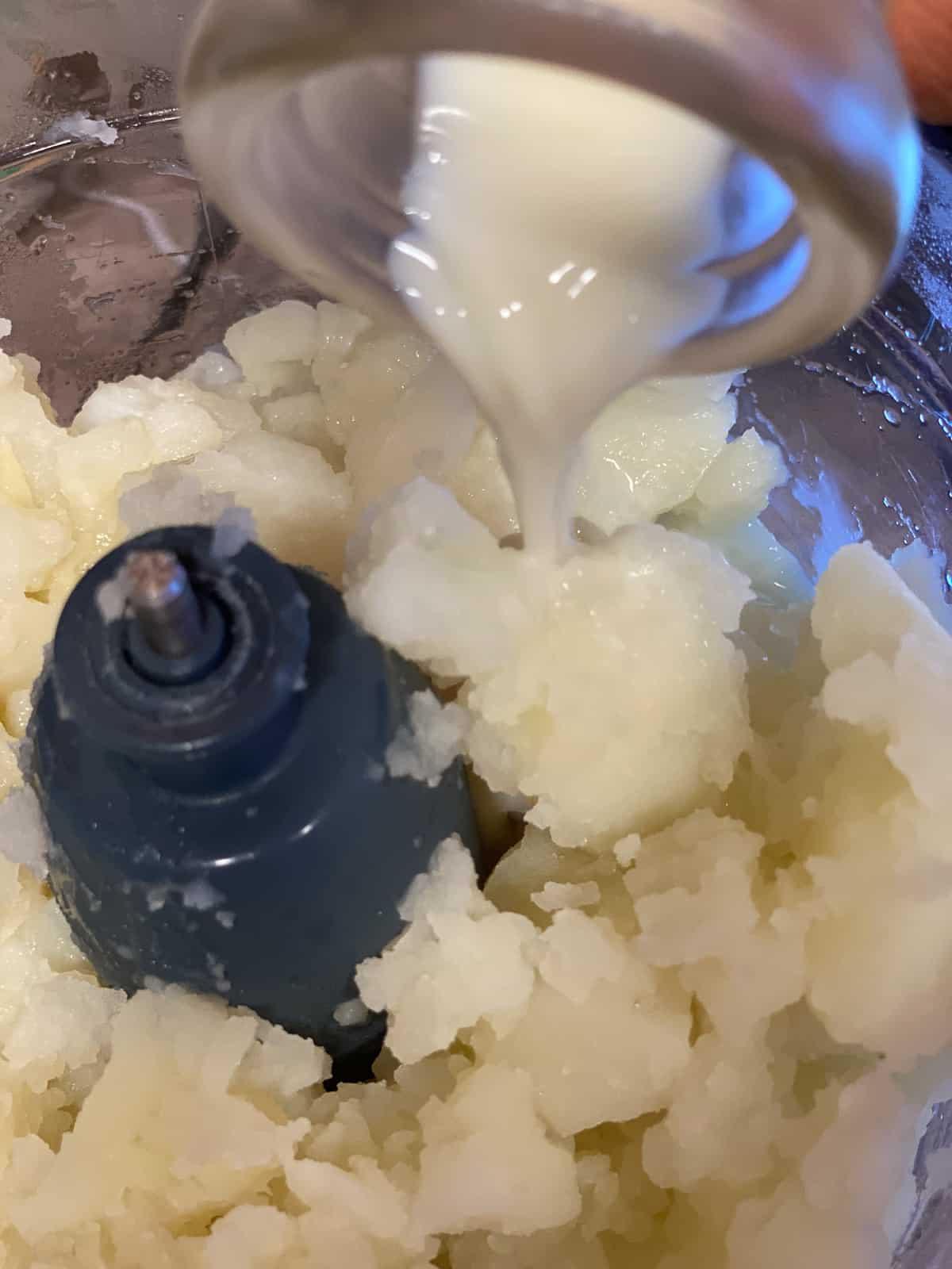 Cremige geröstete rote Paprikasuppe 7 Prozessaufnahme, die das Hinzufügen von Milch zum Food Processor zeigt