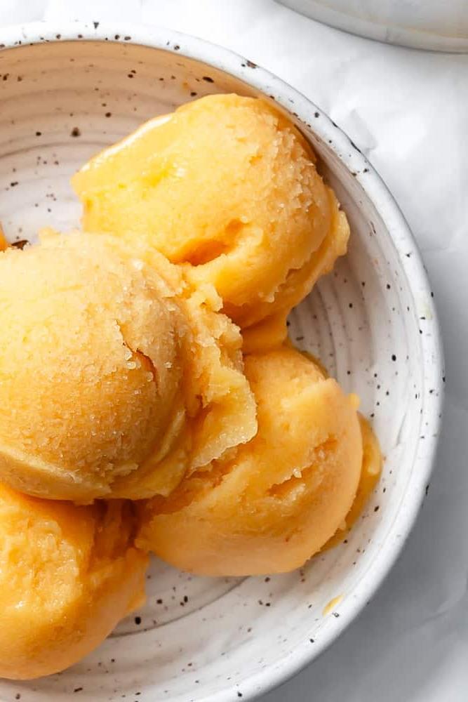 **Pfirsich Sorbet** 7 Nahaufnahme von Kugeln Pfirsich Sorbet in einer weißen Schale.
