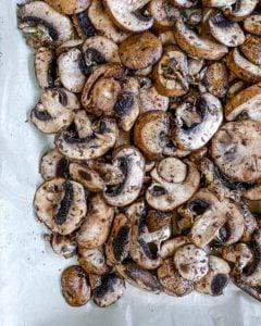 seasoned mushrooms on baking tray with parchment paper prior to being roasted 