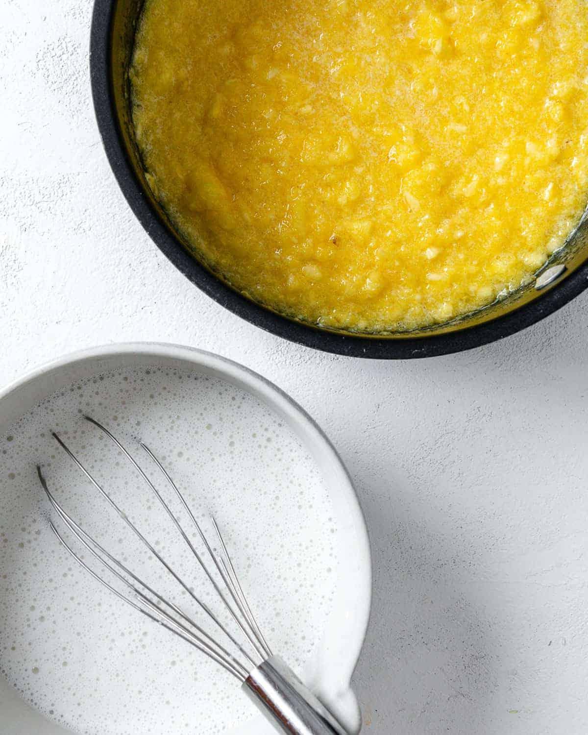 Veganer Kokos-Ananas-Kuchen 7 Kuchenfüllung in schwarzer Pfanne mit weißer Zutatenschale daneben