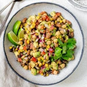 Fertiges Texas Caviar [Avocado-Mais-Bohnen-Salat] auf einem weißen Teller vor hellem Hintergrund