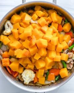 Prozess, der die Zugabe von Butternut-Kürbis zur Schüssel zeigt