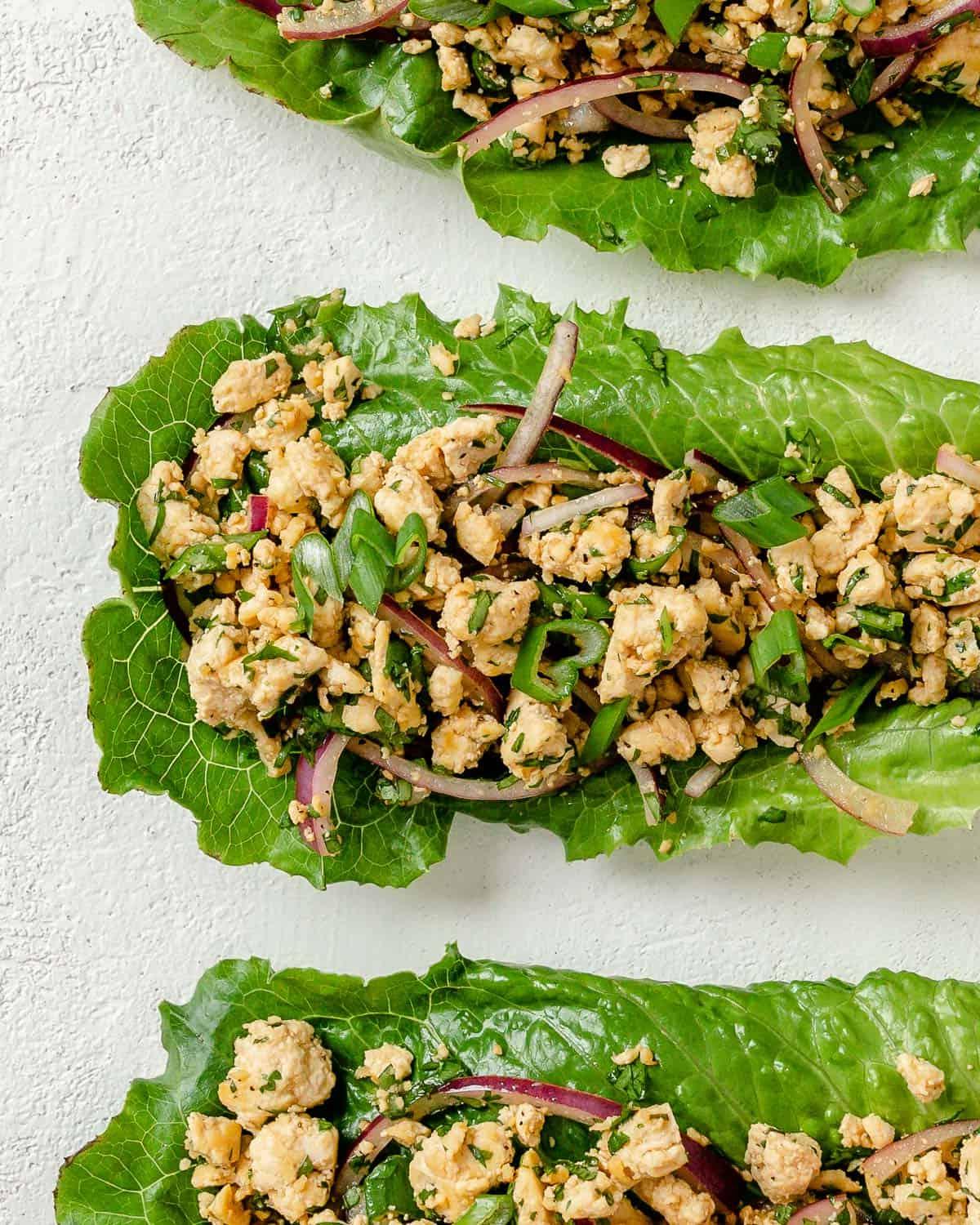 Veganer Tofu-Larb-Salat 8 Drei Portionen Larb Salat auf weißer Oberfläche angerichtet.