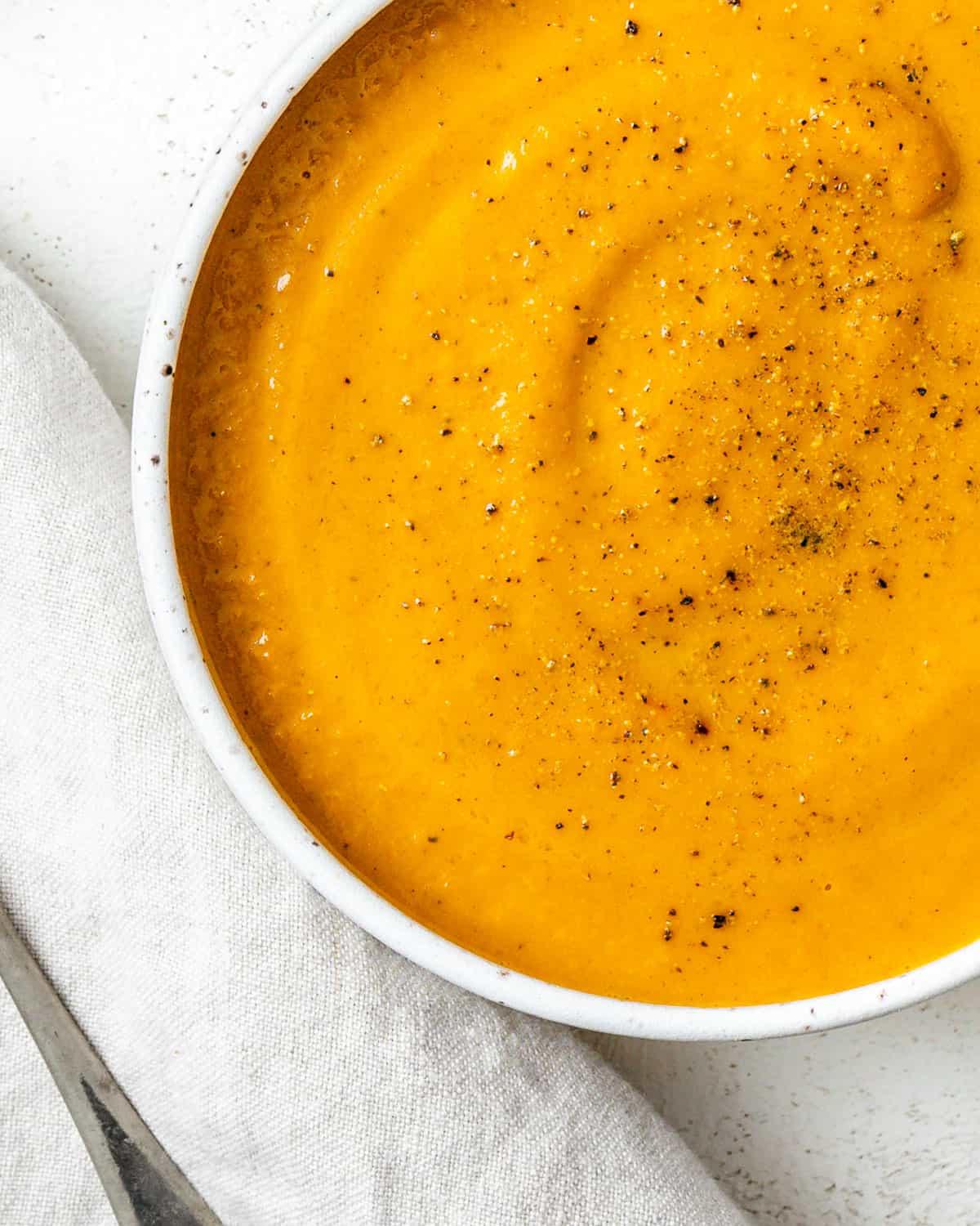 Cremige Curry-Karotten-Ingwer-Suppe 8 Fertige cremige Curry-Karotten-Ingwer-Suppe in einer weißen Schüssel auf weißem Hintergrund.