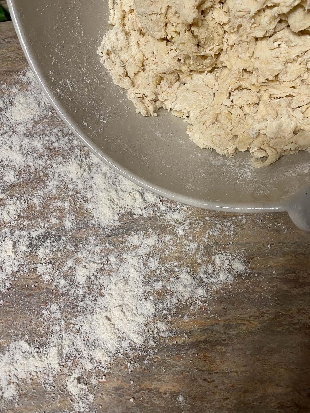 Vegane Pizzaröllchen 7 process of forming flour in a white bowl against a light brown surface