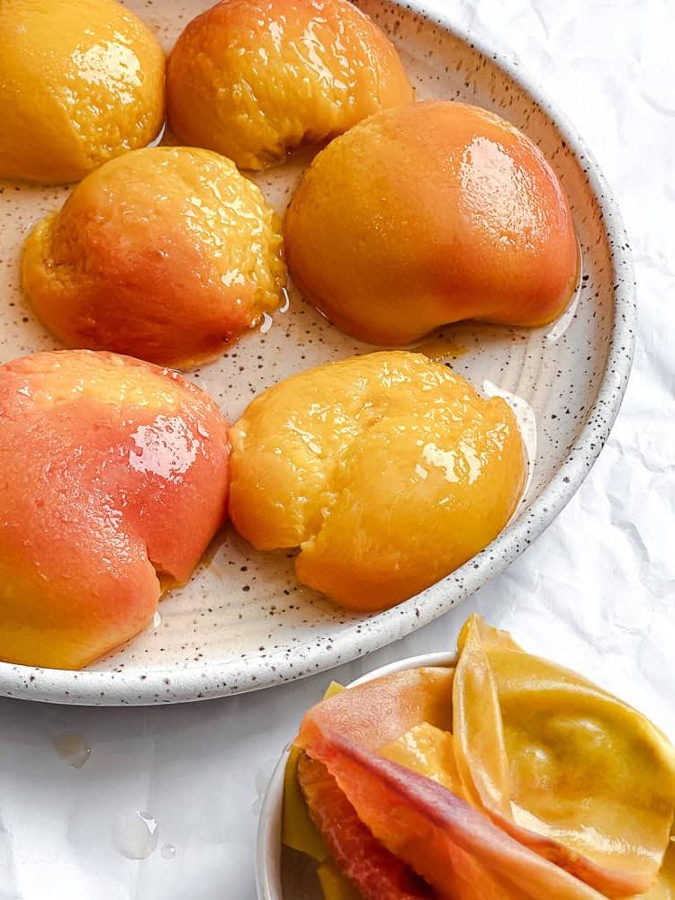 Peach Melba 8 Pochierte Pfirsiche liegen fertig auf einem Teller.
