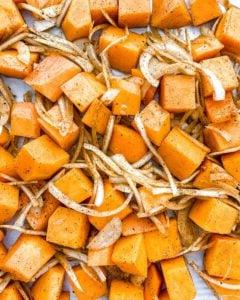 Ungekochter gerösteter Butternut-Kürbis mit indischen Gewürzen und karamelisierten Zwiebeln auf weißer Oberfläche
