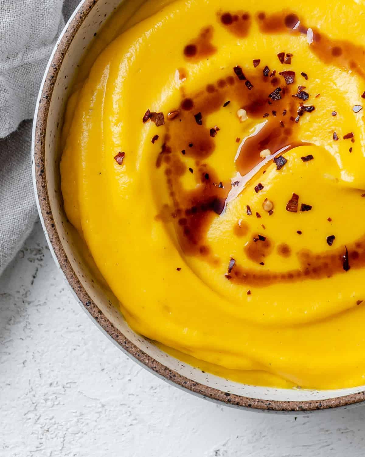 Fertiggestellte einfache vegane Kürbissuppe auf weißem Untergrund